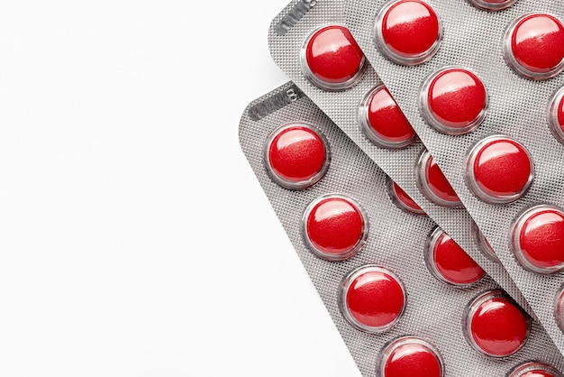 Красные таблетки в упаковке крупным планом аптека лекарства студия выстрел копией пространства на белом фоне