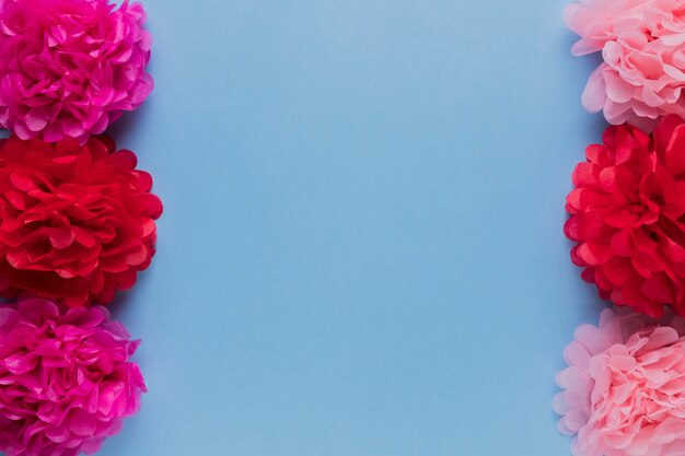 Red and pink decorative flower arrange in row over blue surface