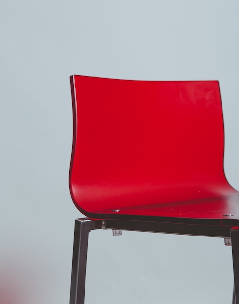 Красный пластиковый стул на белом полу
