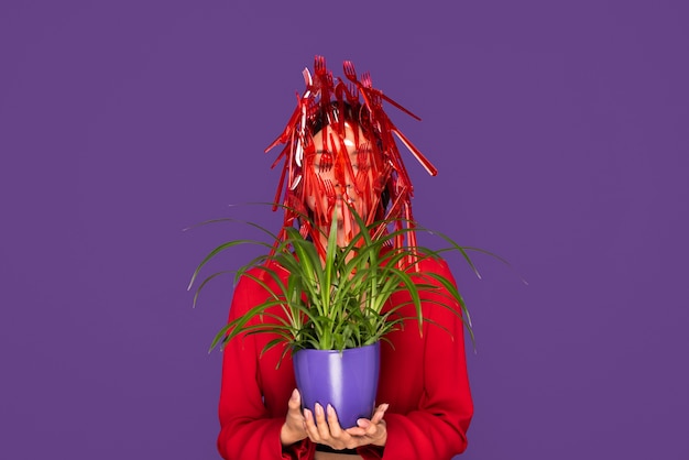 Red plastic tableware on woman who's holding a plant