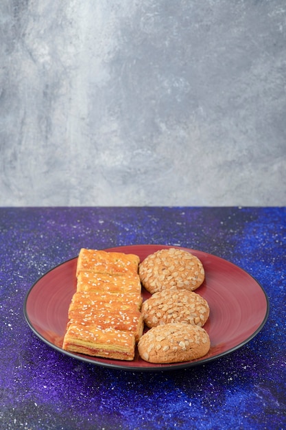 Free photo a red plate with healthy cookies and delicious crackers on galaxy table.