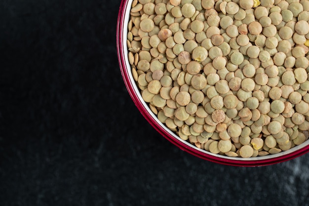 Free photo a red plate with unprepared lentils in a black.