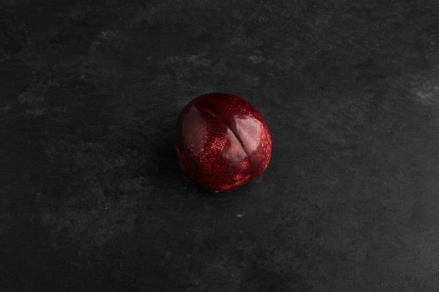 A red plum isolated on black background.