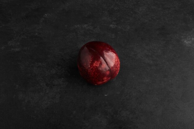 A red plum isolated on black background.