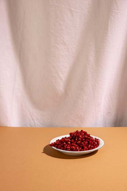 Red pomegranate seeds on plate above brown table