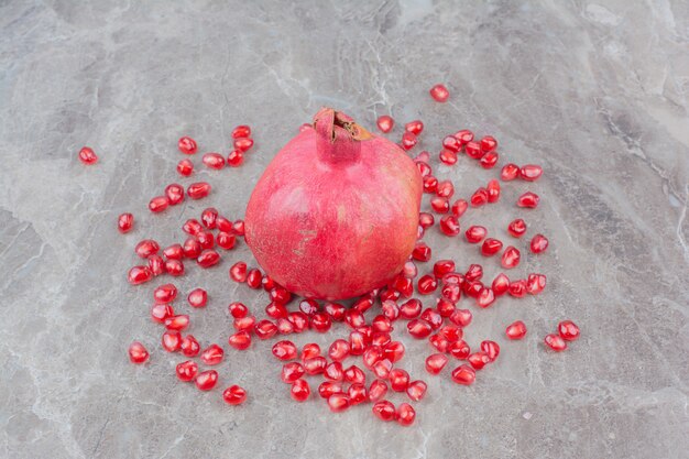 Red pomegranate and seeds on stone background. 