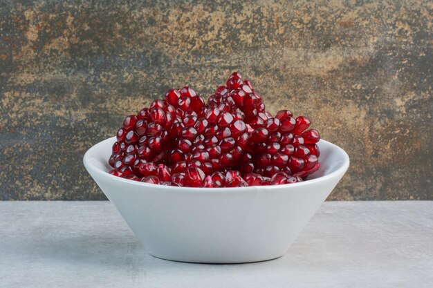 하얀 그릇에 붉은 석류 씨앗. 고품질 사진