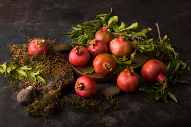 Red pomegranates with green leaves on marble