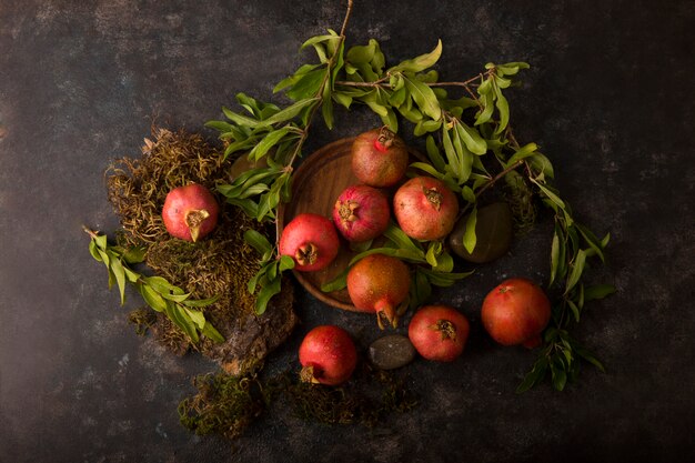 Red pomegranates on the wooden board, top view