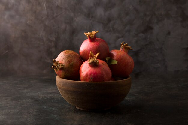 Red pomegranates in a wooden platter on marble