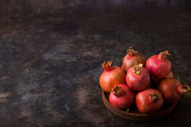 Red pomegranates in a wooden platter on marble