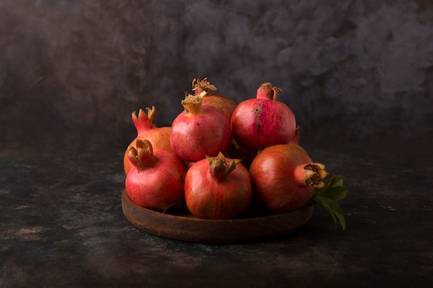 Free photo red pomegranates in a wooden platter