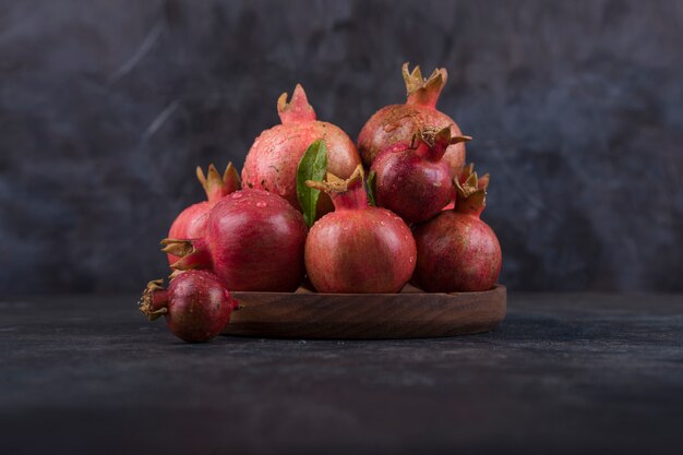 Red pomegranates in a wooden platter