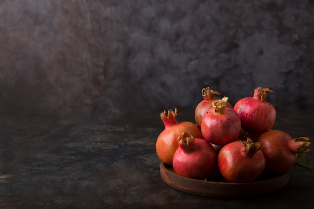 Red pomegranates in a wooden platter
