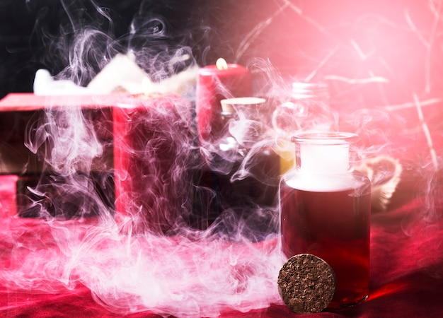 Free photo red potion and halloween decorations in smoke