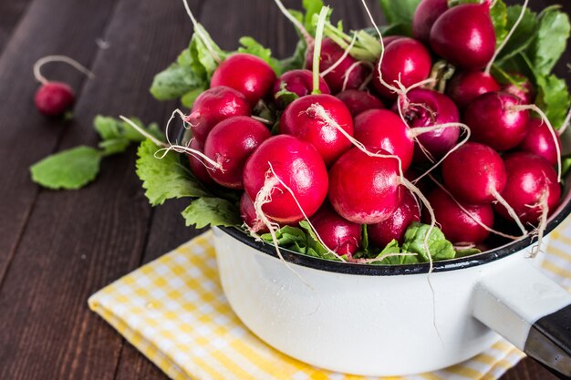 Red radishes in bowl on wood table