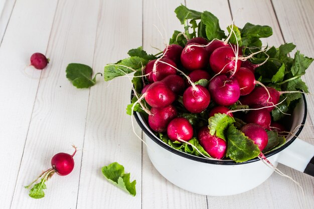 Red radishes in bowl on wood table