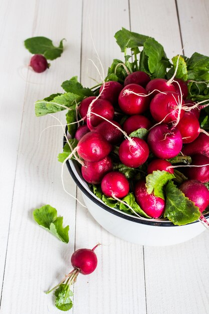 Red radishes in bowl on wood table