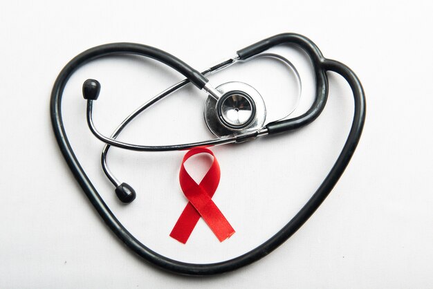 赤いリボンと白い背景の聴診器。 HIVエイズリボンの認識
