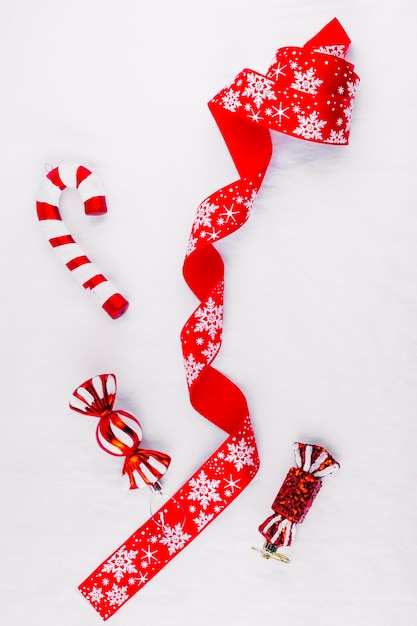 Red ribbon with toy candies on table 