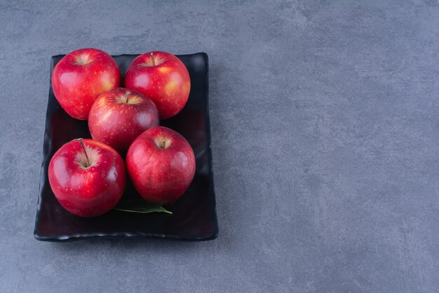 大理石のテーブルの上の木の板に赤い熟したリンゴ。