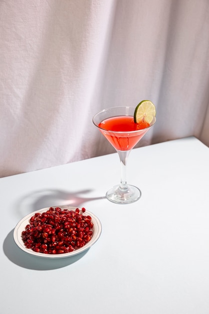 Red ripe pomegranate seeds with cocktail drink on white desk