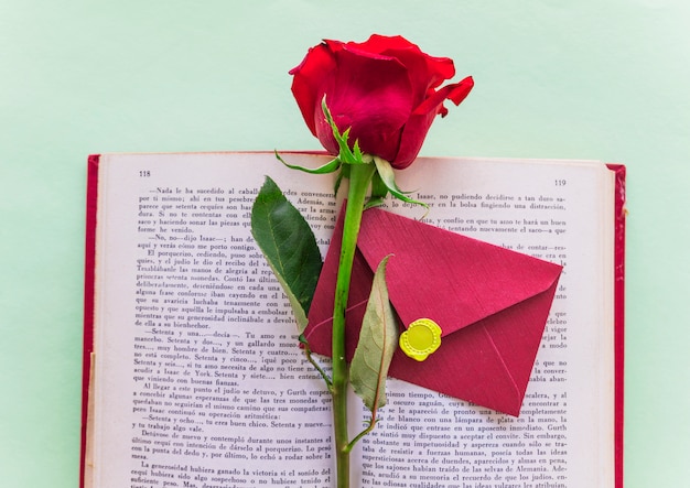 Foto gratuita ramo di rose rosse con busta sul grande libro