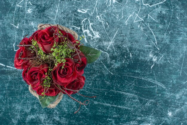 Red rose in a bucket , on the blue background.