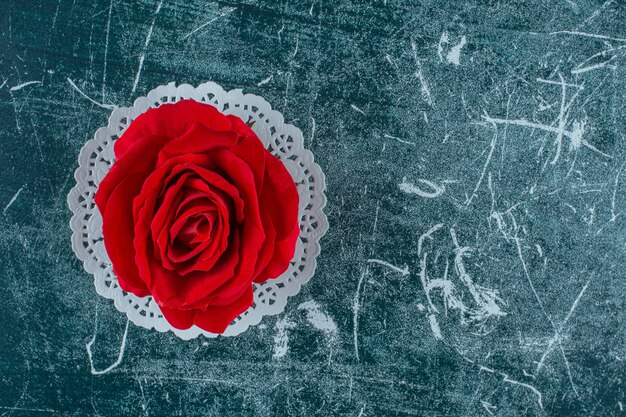 Red rose on a coaster , on the blue background.