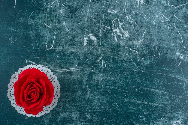 Red rose on a coaster , on the blue background.