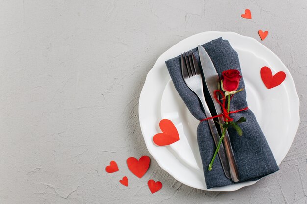 Red rose with cutlery on light plate