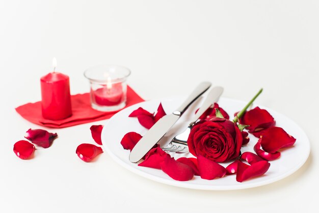 Red rose with cutlery on plate 