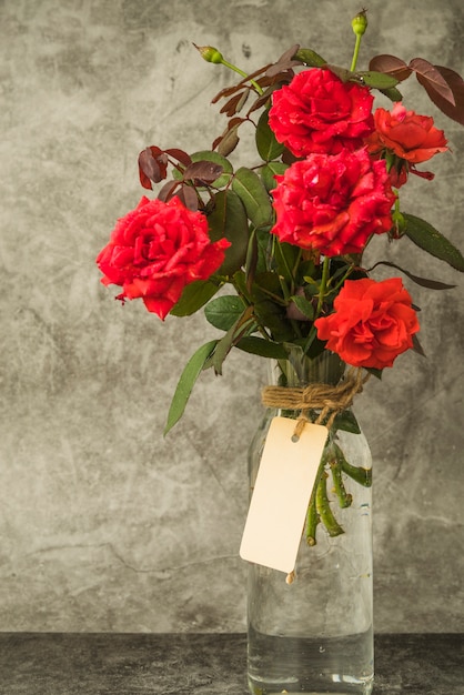 Red roses bouquet in the glass bottle with blank tag