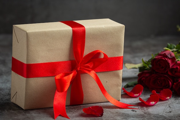 Red roses and gift box on dark background