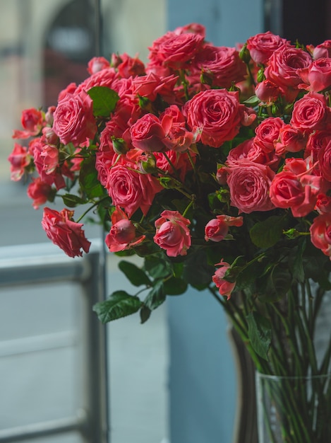 Красные розы внутри прозрачной стеклянной вазы в комнате.