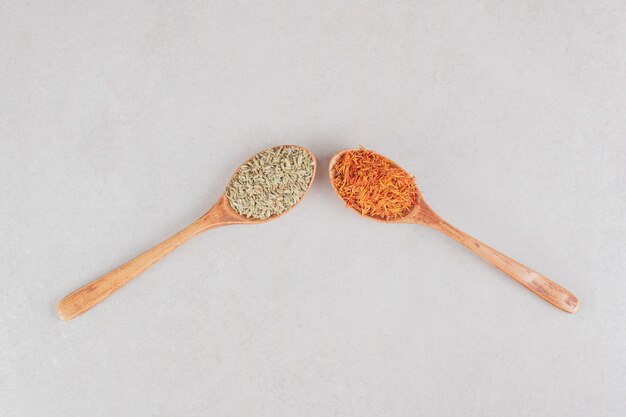 Red saffron seeds in a wooden spoon.