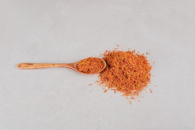 Red saffron seeds in a wooden spoon.