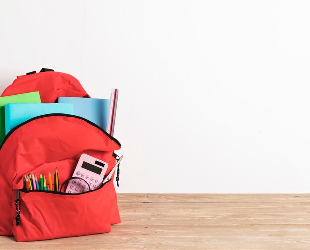 Red school bag with essential supplies 