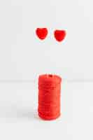 Free photo red sewing spool with two hearts on sticks