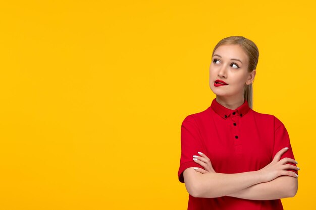 Red shirt day cute girl thinking with crossed hands in a red shirt on a yellow background