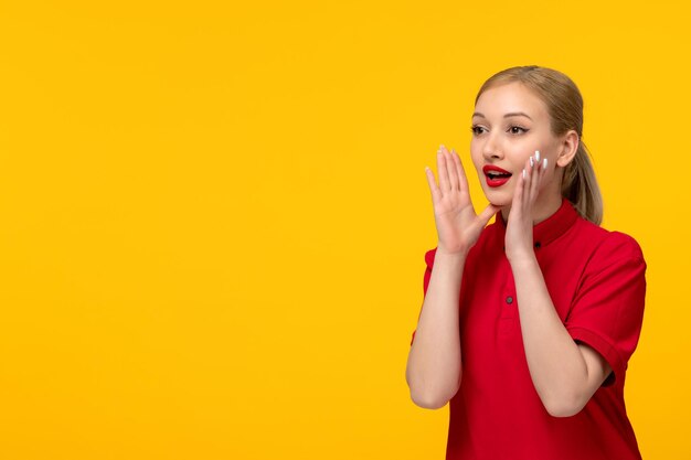 Red shirt day pretty blonde girl calling for help in a red shirt on a yellow background