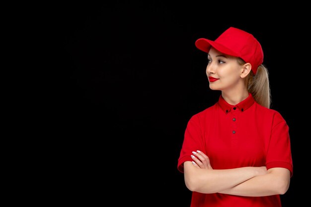 Foto gratuita ragazza sorridente di giorno della camicia rossa con le mani incrociate in un berretto rosso che indossa una camicia e un rossetto luminoso