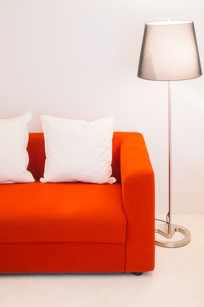Красный диван с подушкой и лампой