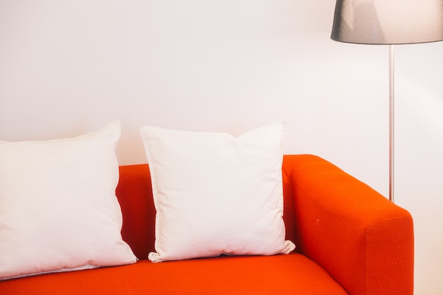 枕と光のランプが付いている赤いソファ