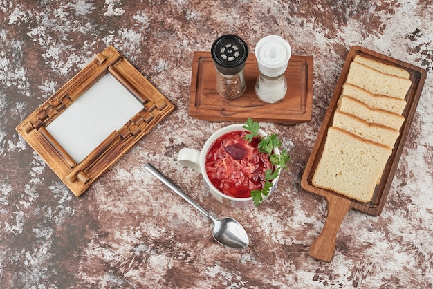 Red soup with herbs served with bread, top view.