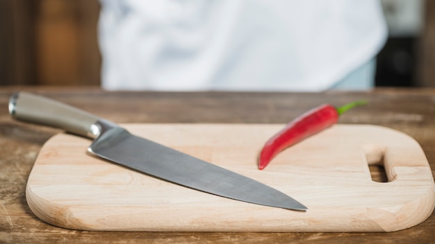 Red spicy chili pepper and sharp knife on chopping board