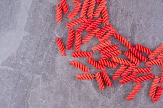 Red spiral pastas on marble space. 