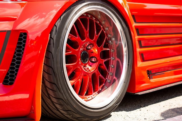 Бесплатное фото Красный спортивный настроенный автомобиль вид сзади колеса, крупным планом. день модных автомобилей в дороге