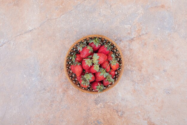 Free photo red strawberries in a rustic wooden cup.