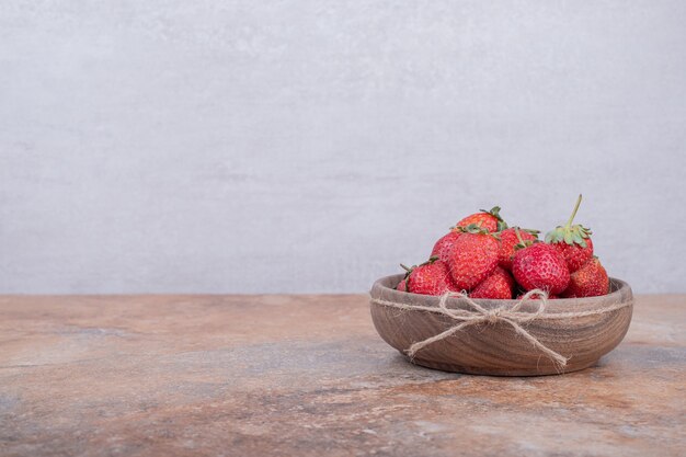 Red strawberries in a rustic wooden cup.